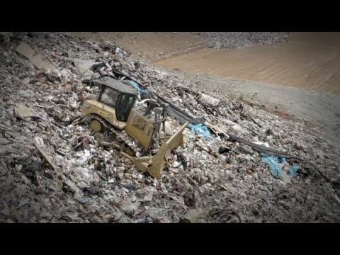 Cat® D6 XE Dozer Pushing Trash Downhill in a Landfill
